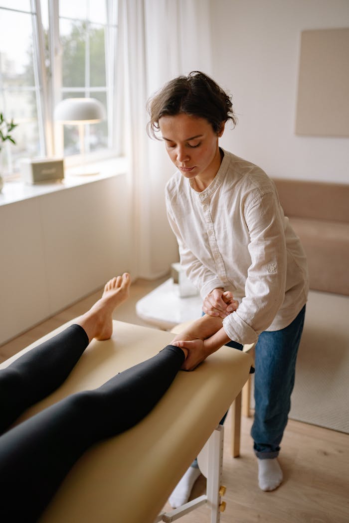A therapist provides a leg massage to a woman in a calm, serene indoor environment.